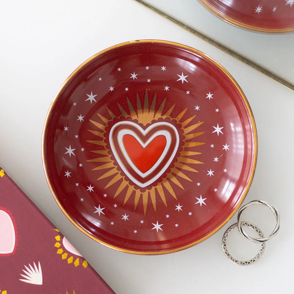 Ceramic sacred heart trinket dish with red heart and flames design holding jewellery and keys on white background