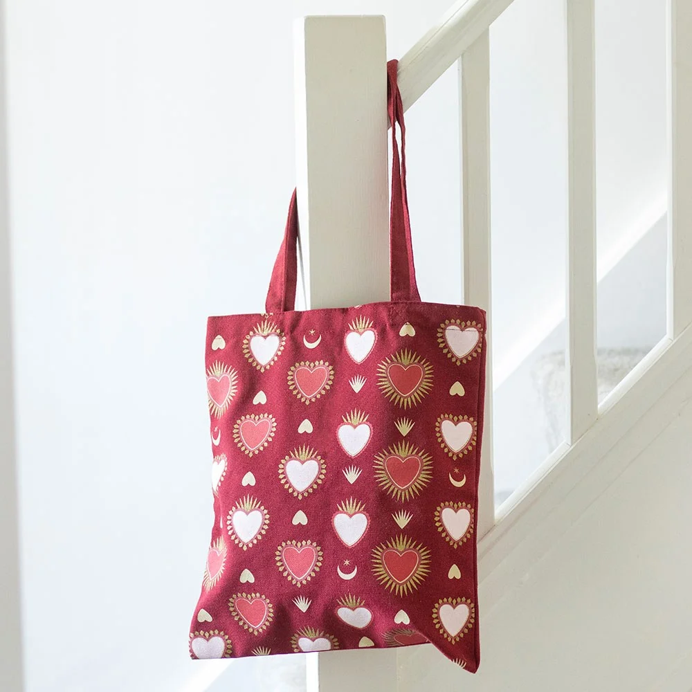 Sacred Heart tote bag with radiant heart prints, beige fabric, shown flat on white background