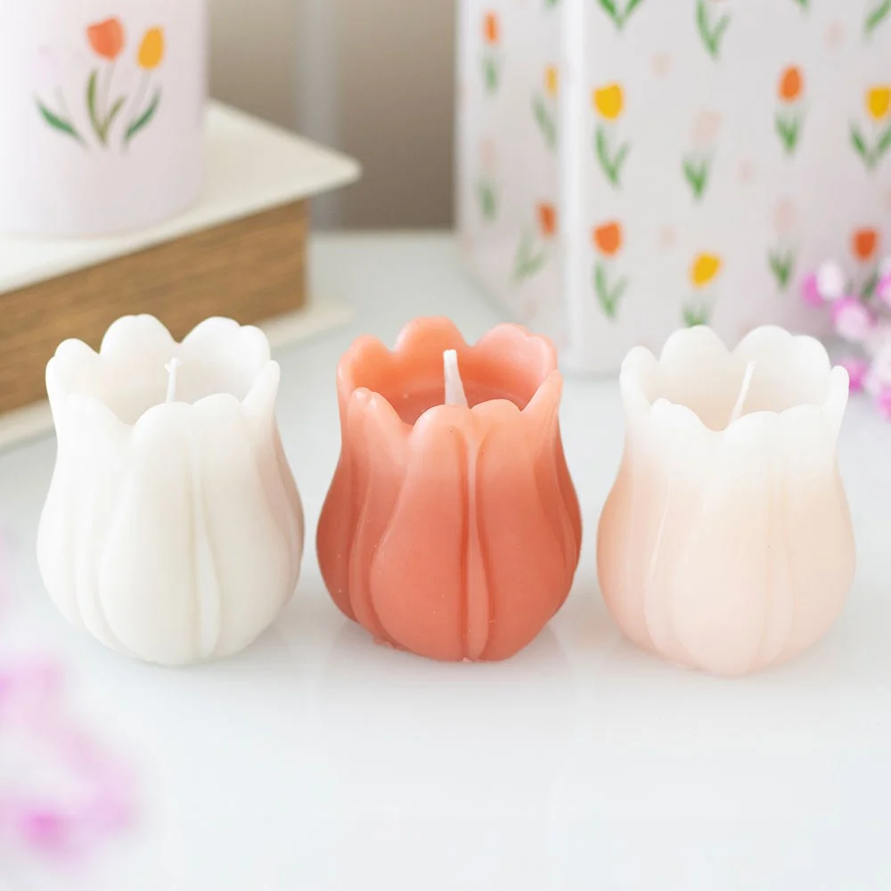 Set of three unscented tulip shaped candles in soft pastel colors on a white background