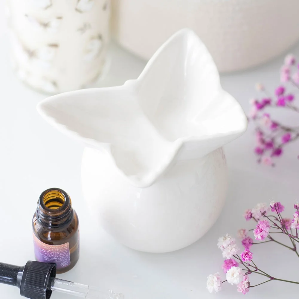 White ceramic oil burner with a butterfly-shaped bowl topper and classic sculptural silhouette on a white background