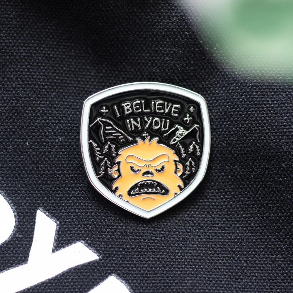 Bigfoot enamel pin showing a cartoon Bigfoot silhouette with green background, perfect for jackets or backpacks
