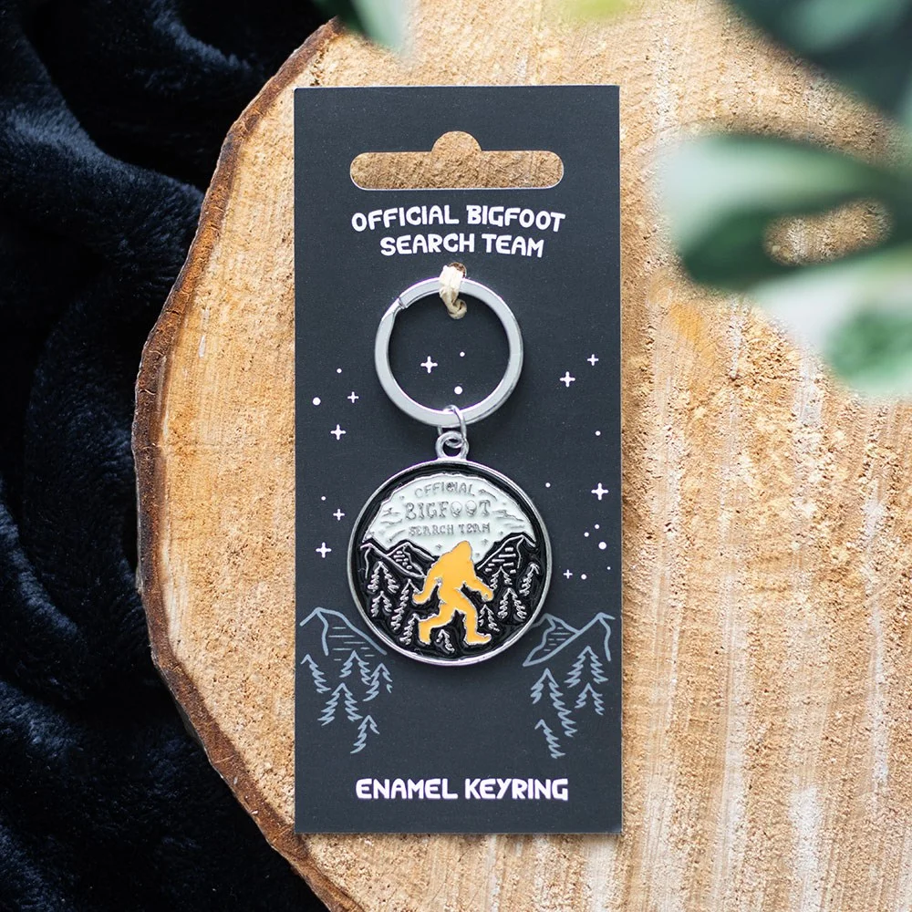 Enamel Bigfoot keyring featuring a cartoon Bigfoot and "Bigfoot Search Team" text on a metal ring