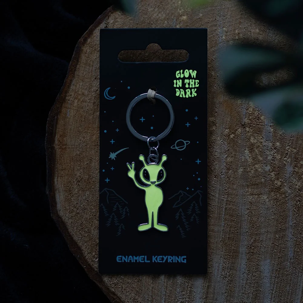 Glow in the dark keyring featuring a small green alien holding a silver keyring loop against a white background