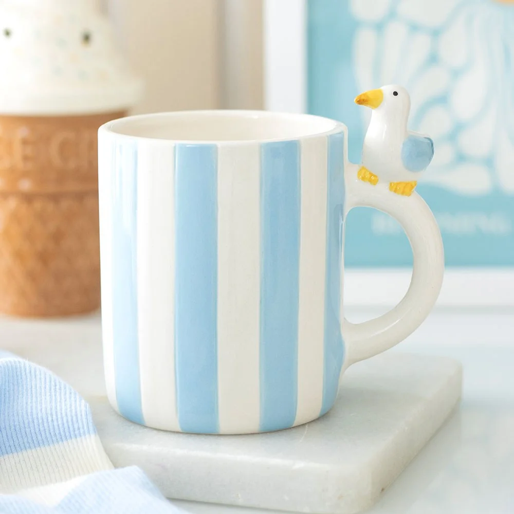 Striped ceramic mug with soft pastel bands and a cheeky seagull illustration, 370ml capacity, coastal theme