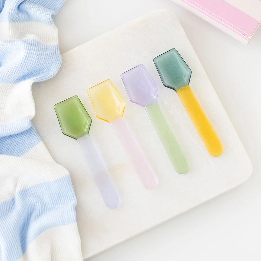 Set of 4 pastel glass dessert spoons in soft colors arranged on a white surface for serving desserts