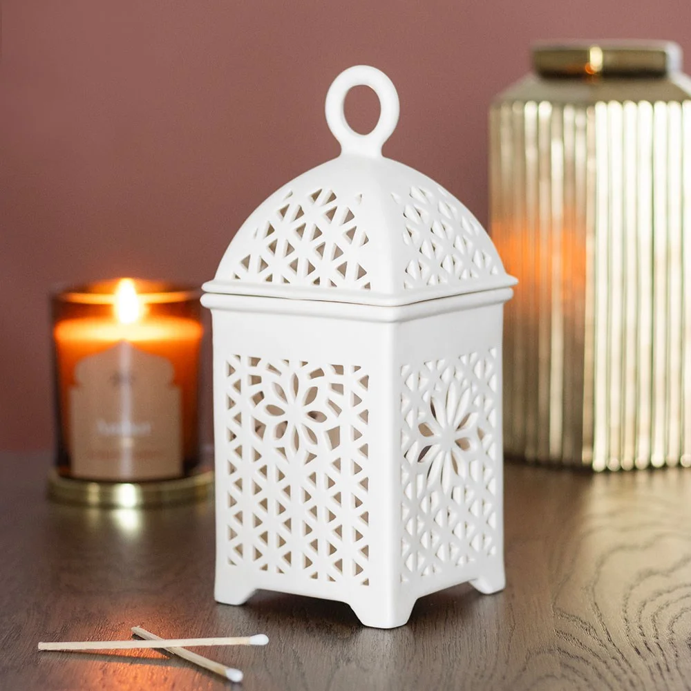 Ceramic fragrance burner shaped like a traditional lantern with intricate cut-out details and removable lid on white background