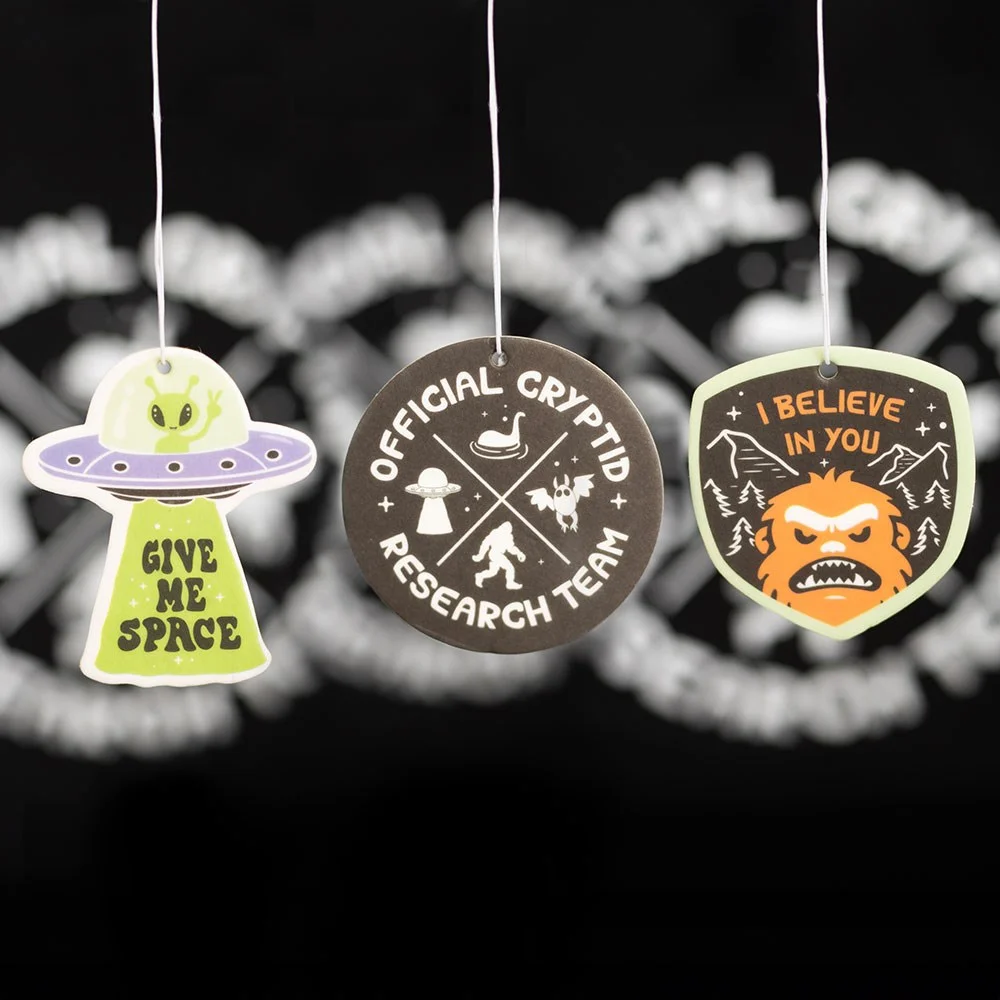 Set of 6 cryptid scented air fresheners with designs like Give Me Space and I Believe in You in green apple and pine scents