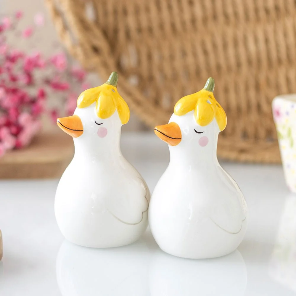 Ceramic salt and pepper shakers shaped as two ducks wearing spring flower hats on a white background