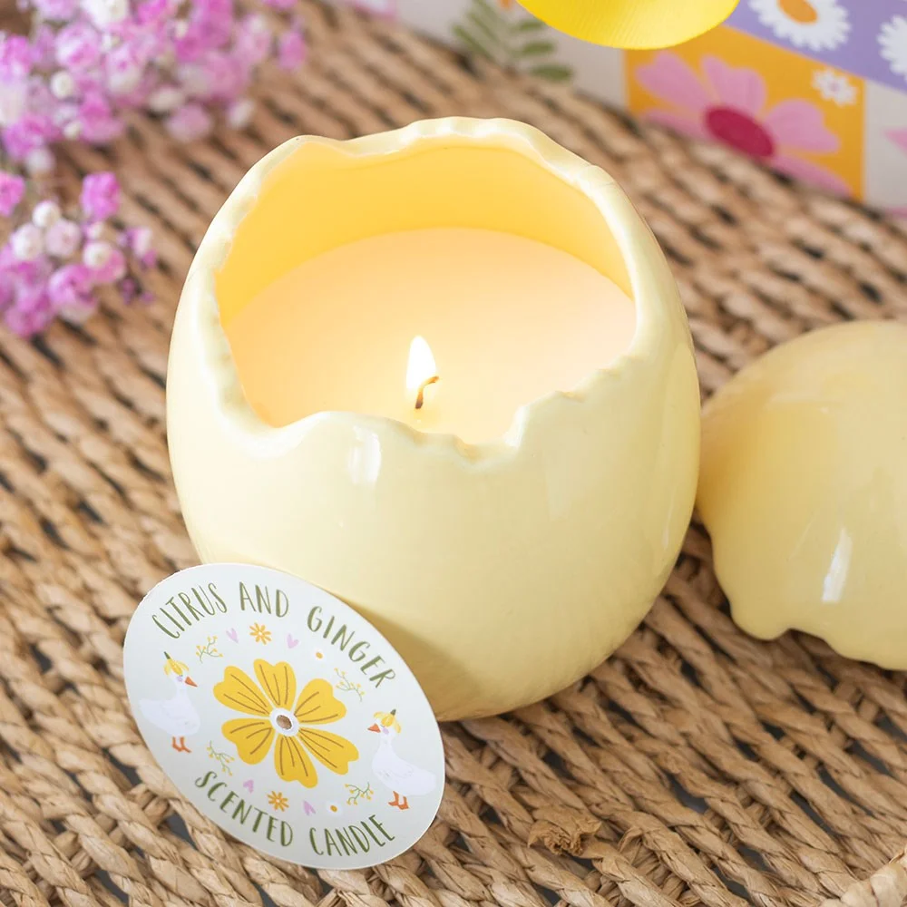 Yellow cracked egg-shaped citrus ginger candle on white background, designed for spring and Easter décor.