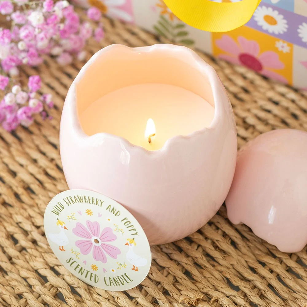 Pink cracked egg-shaped wild strawberry candle with poppy scent on white background