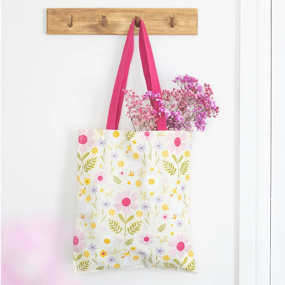 Daisy print tote bag with floral design and bright pink handles made from lightweight polycotton blend