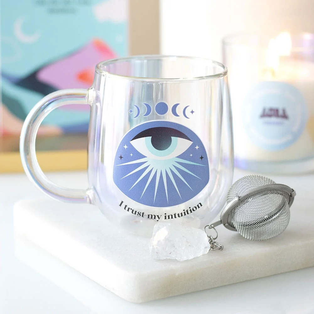 Double walled glass mug with all-seeing eye design and matching aura crystal tea infuser on white background