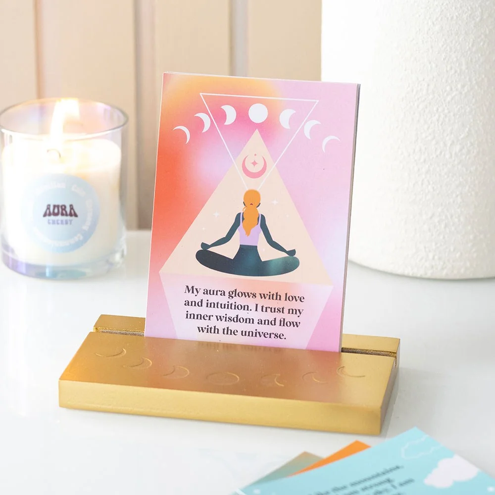 Set of 10 vibrant aura affirmation cards displayed on a gold-tone wooden stand with inspirational illustrations and phrases