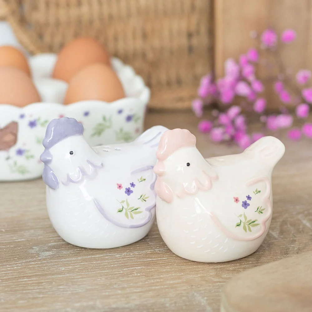 Ceramic hen salt and pepper shakers in soft pastel tones with simple floral accents on a white background