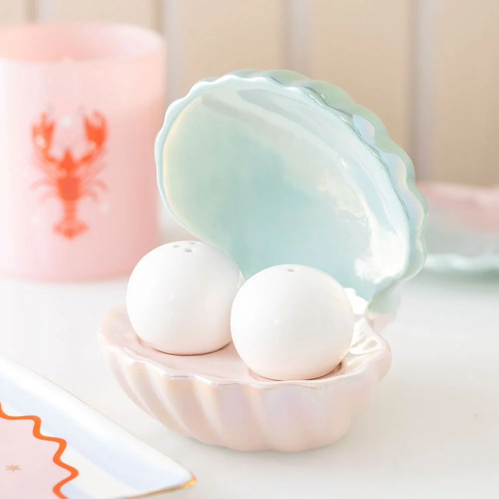 Iridescent clam shell salt shakers holding pearl-like salt and pepper containers with a shiny finish