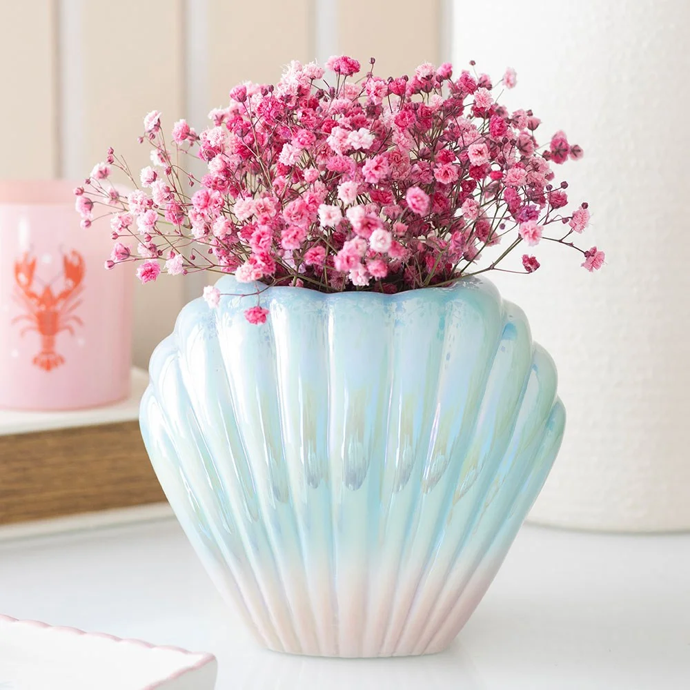 Iridescent shell vase shaped like a flower with a glossy, shimmering finish on a white background