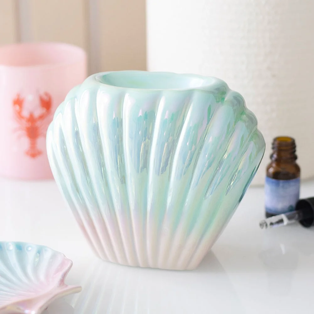 Iridescent shell oil burner in ceramic with glossy pastel finish, shaped like a mermaid shell for home fragrance use