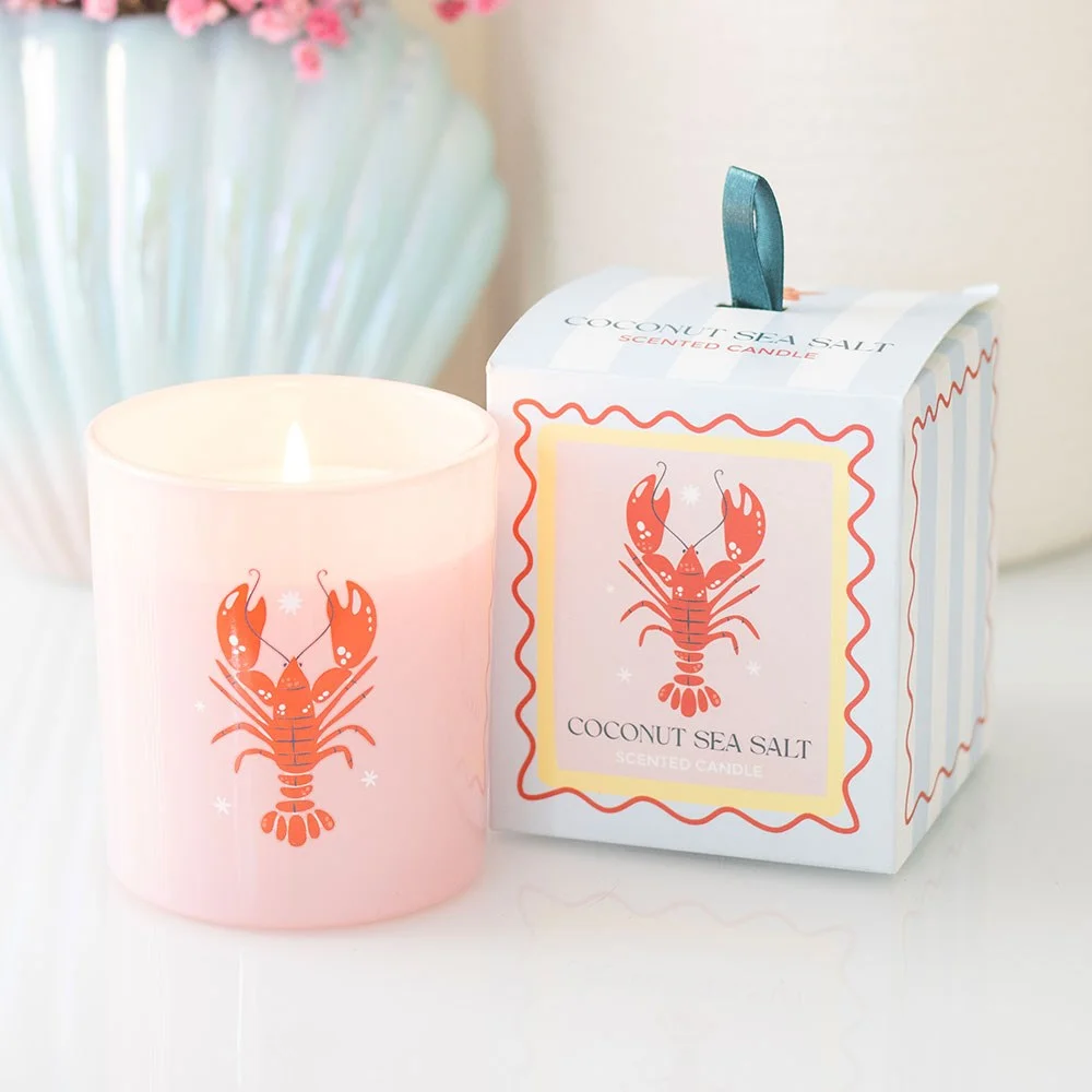 Pastel lobster candle in glass jar with lobster design, next to pastel-striped gift box on white background