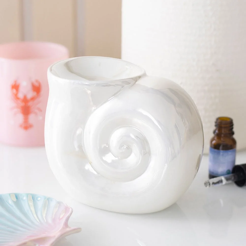 Pearlescent spiral shell ceramic oil burner with soft glaze, shown on white background for home fragrance use