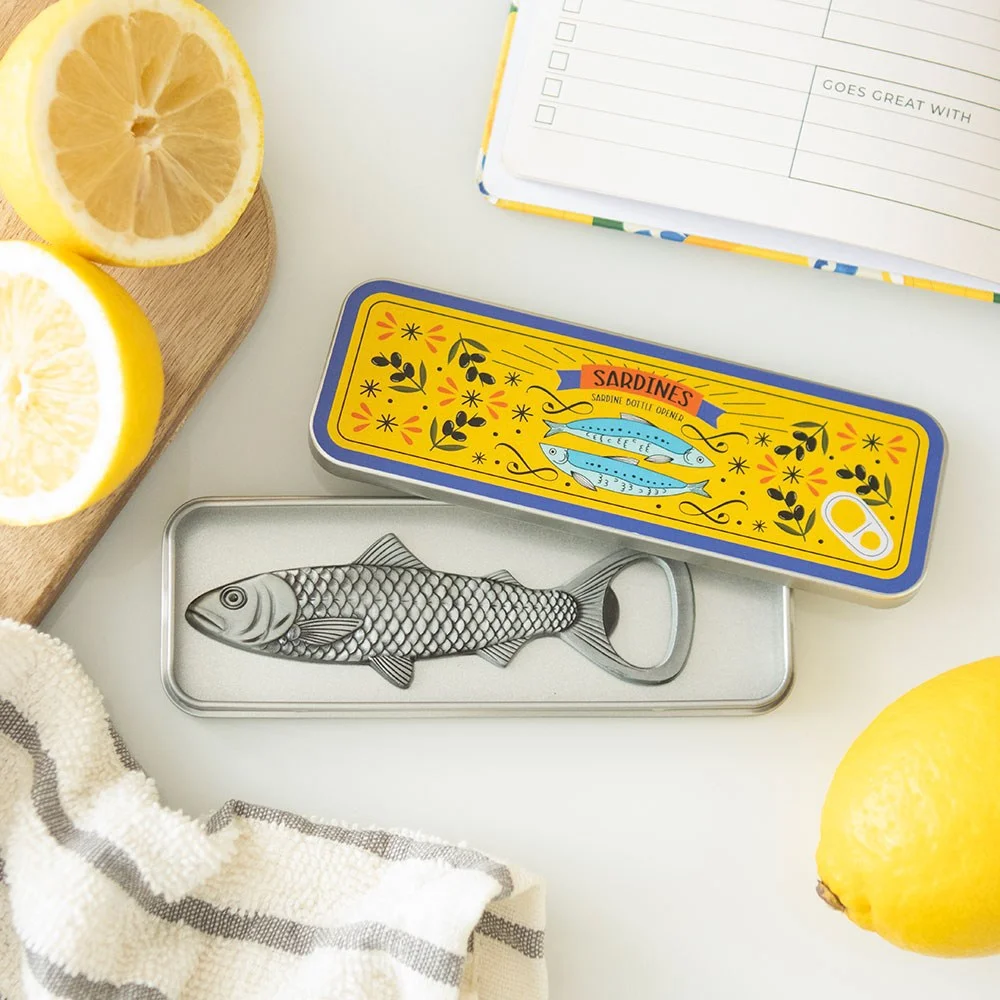 Novelty bottle opener shaped like a sardine inside a small metal storage tin with a nautical design