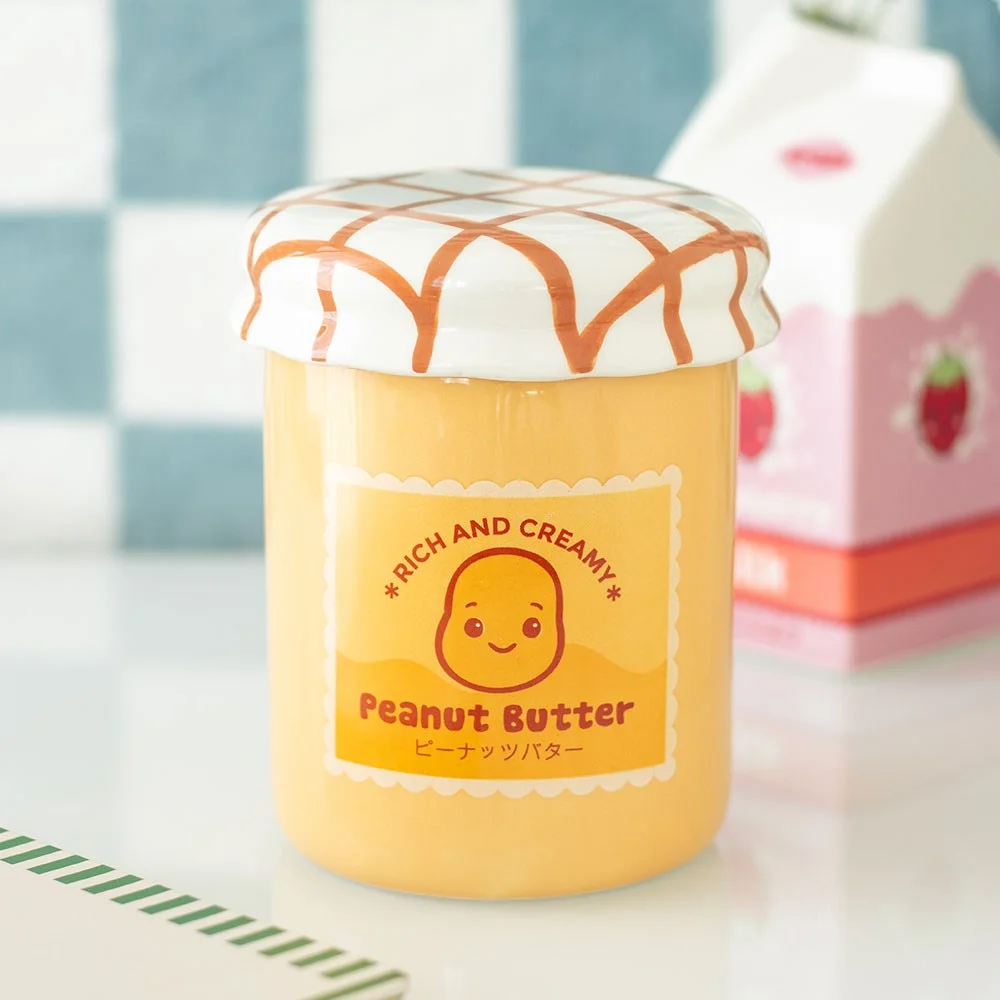 Ceramic oil burner in the shape of a peanut butter jar, cute smiling face and colorful label, tealight visible at the back with lid on