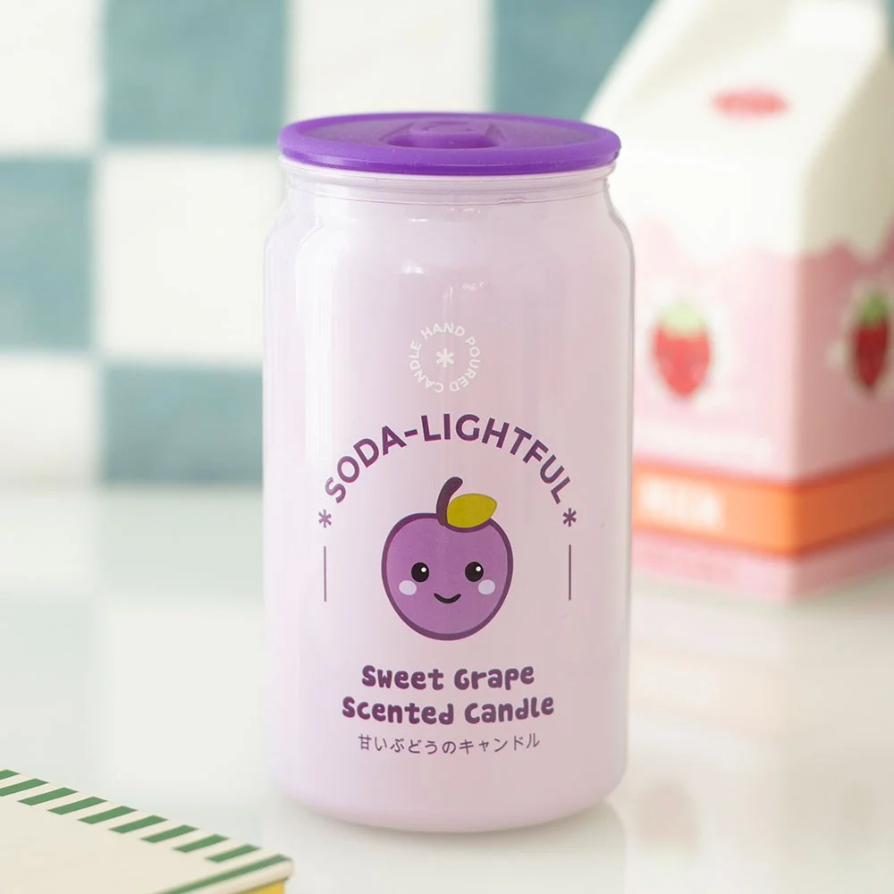 Purple soda‑can shaped grape scented candle with a cute kawaii grape graphic, sitting on a small surface.