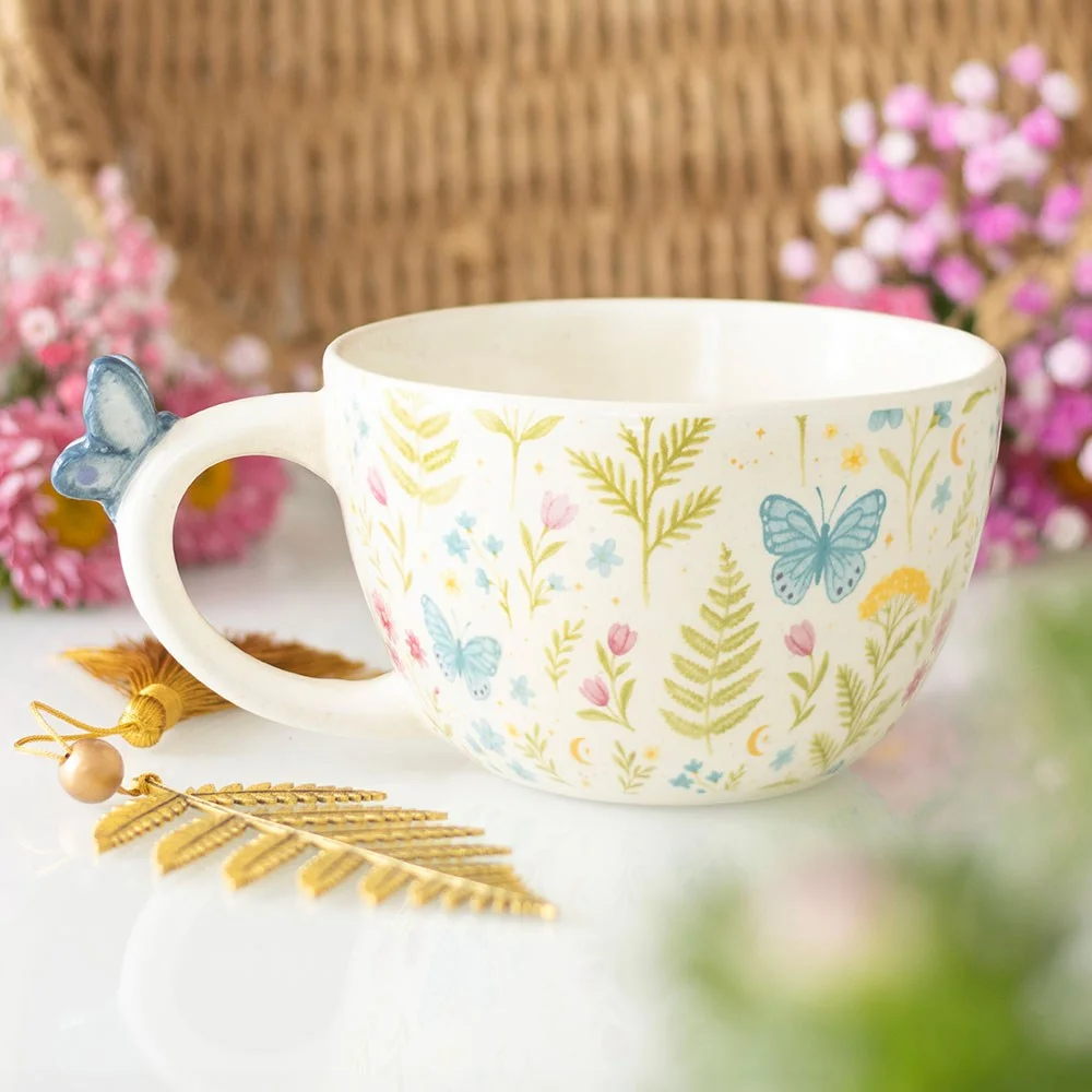 Large ceramic floral print mug with pastel flowers and a blue butterfly on the handle against a white background