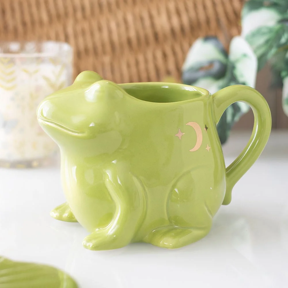 Ceramic frog shaped mug with bright green glaze and detailed frog face, ideal for quirky homeware lovers