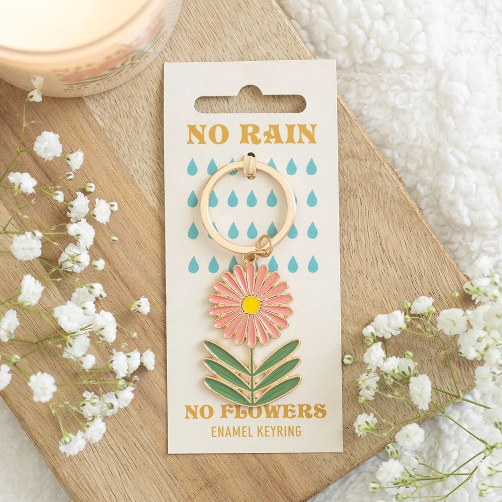 Retro enamel No Rain No Flowers keyring with bold motto in vivid colors, attached to a keychain.