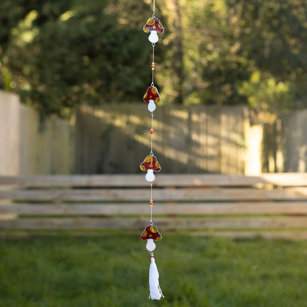 String of resin mushroom suncatchers with colorful beads and white tassel, hung to brighten a window.