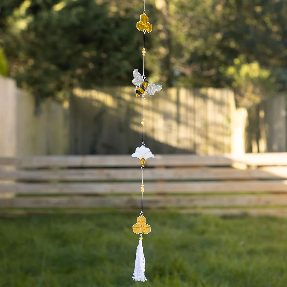 Bee suncatcher string with resin bee, honeycomb and flower details, bright yellow beads and white tassel hanging.