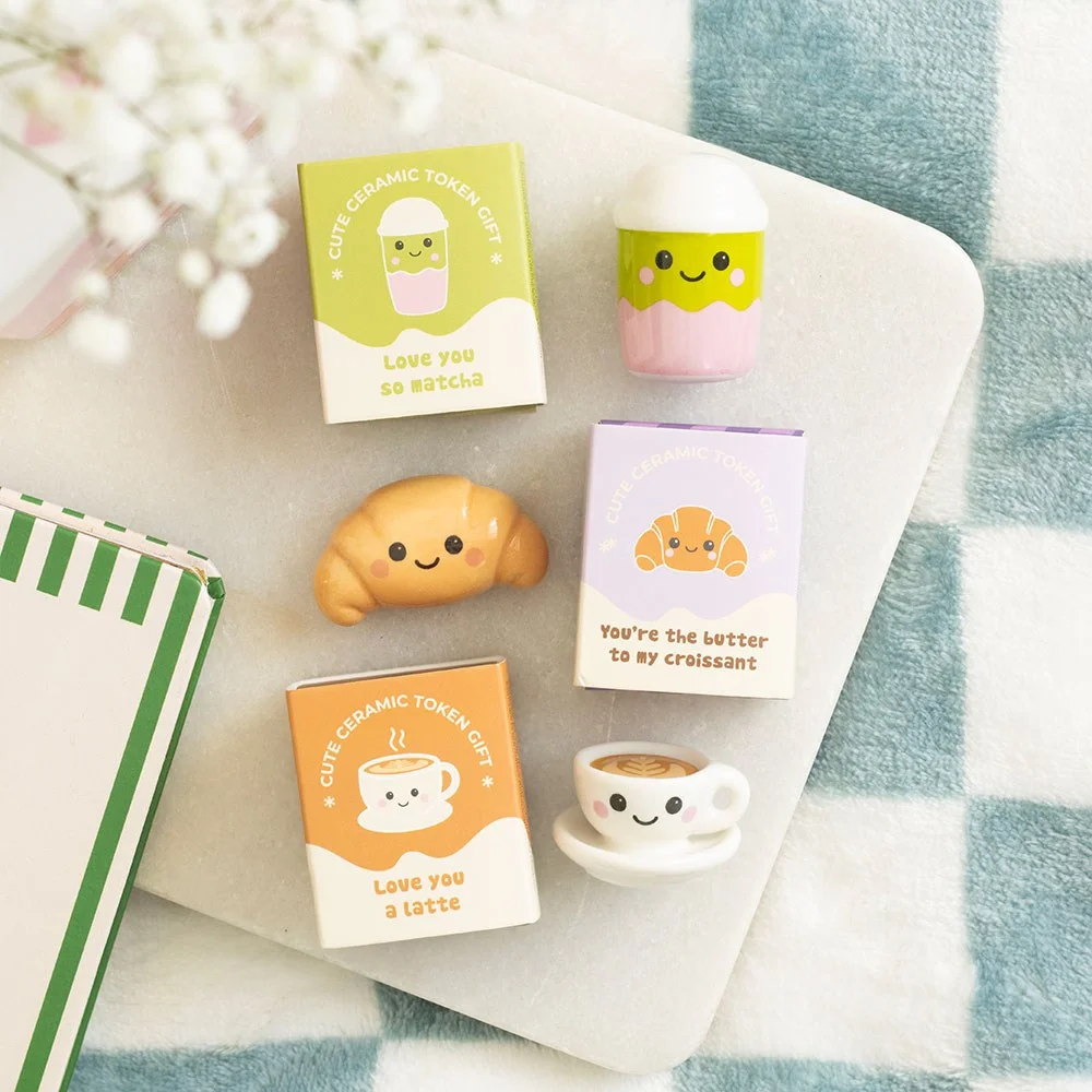 24 kawaii ceramic tokens in bright boxes featuring latte, matcha, and croissant designs displayed on cardboard