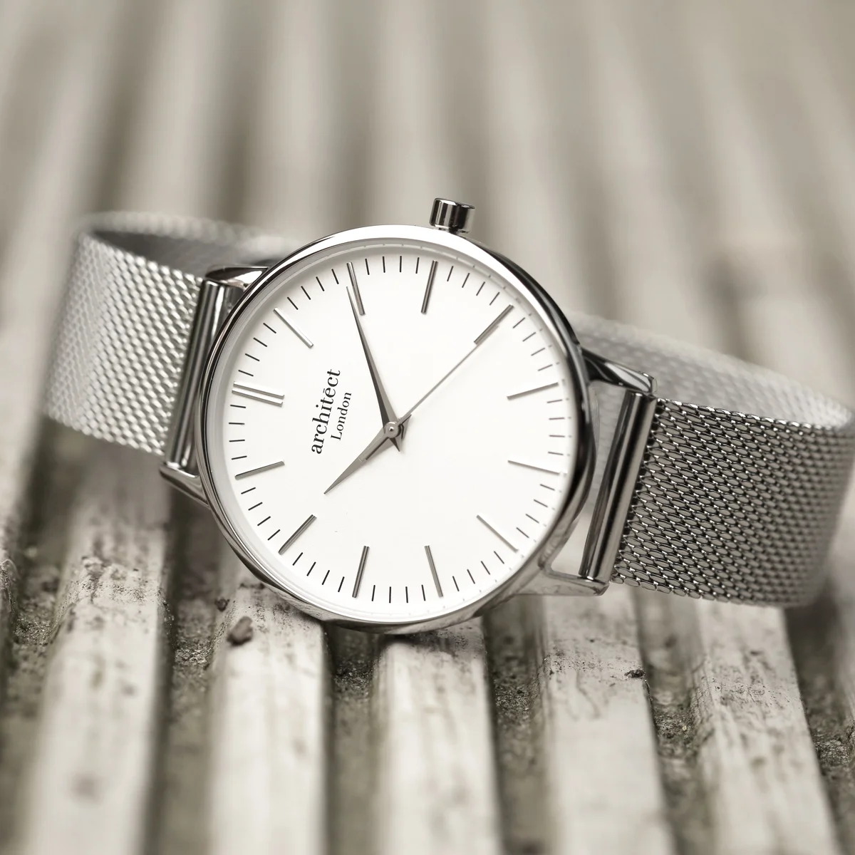 Ladies silver bezel watch with minimalist white dial and silver mesh strap on a white background