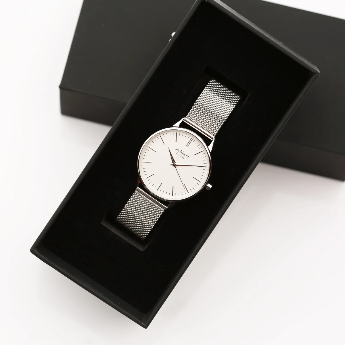 Ladies silver bezel quartz movement watch with minimalist dial and silver mesh strap on white background