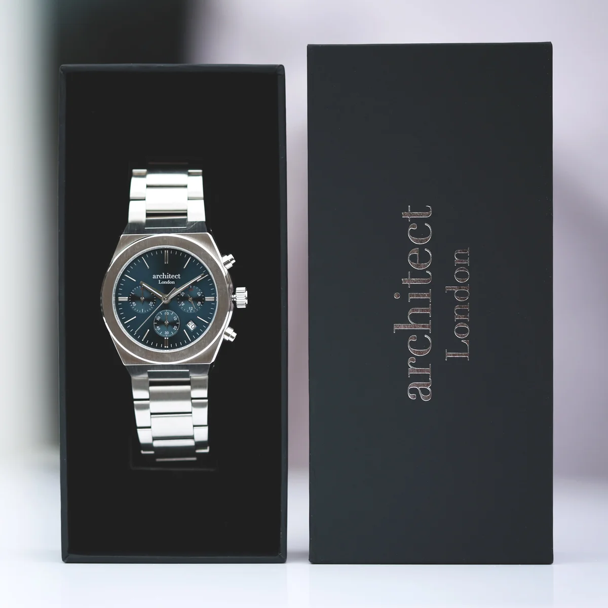 Engraved gift watch showing deep blue dial, silver stainless steel band, and modern font engraving on back plate