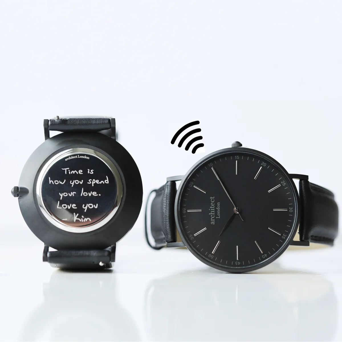 Men's minimalist watch with jet black strap and sleek round face showing contactless payment feature and engraving option