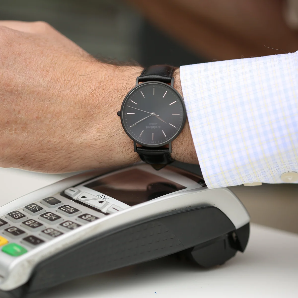 Men's contactless payment watch with minimalist black face, jet black strap, and modern font engraving on dial