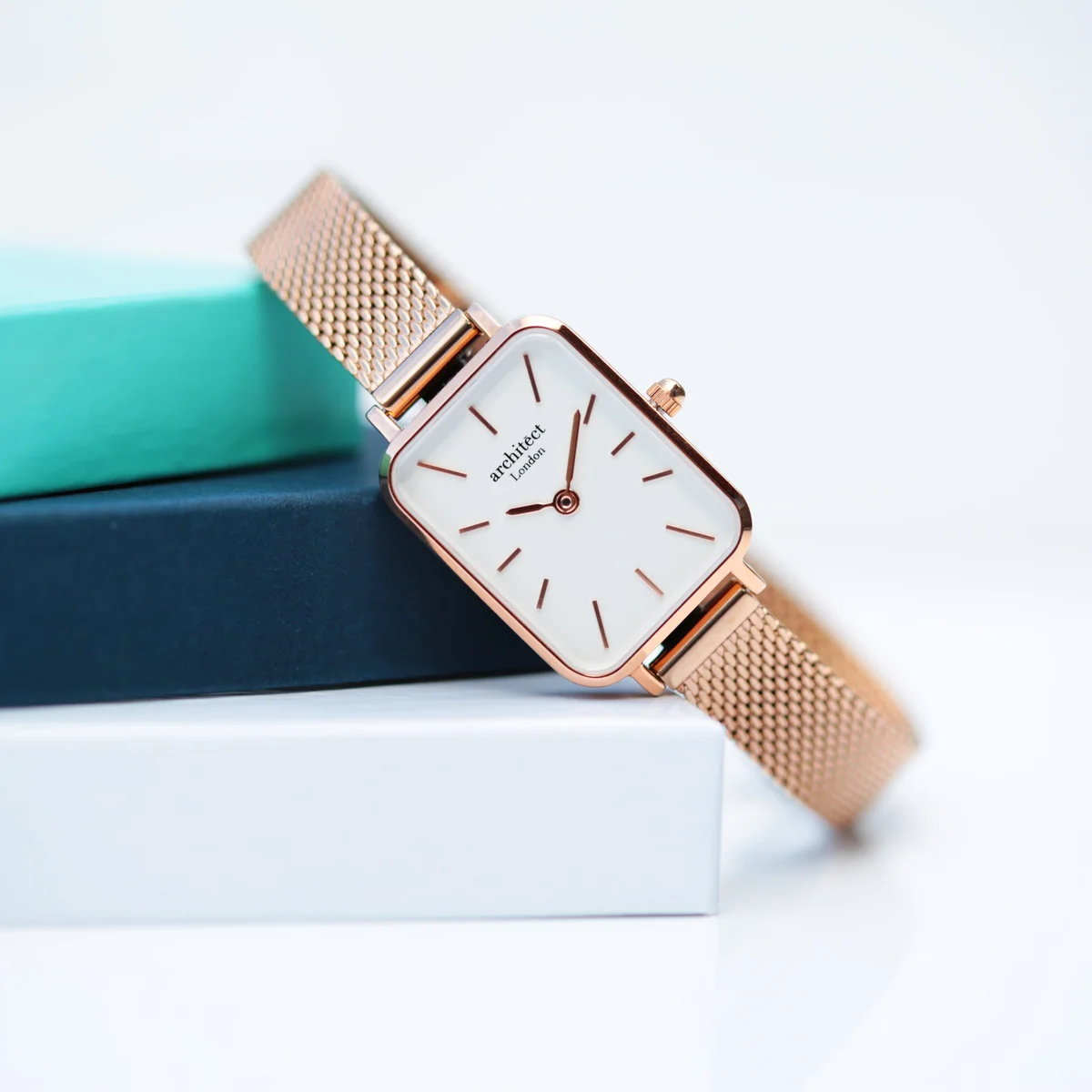 Ladies rose gold watch with minimalist dial, stainless steel case, and handcrafted mesh strap on white background