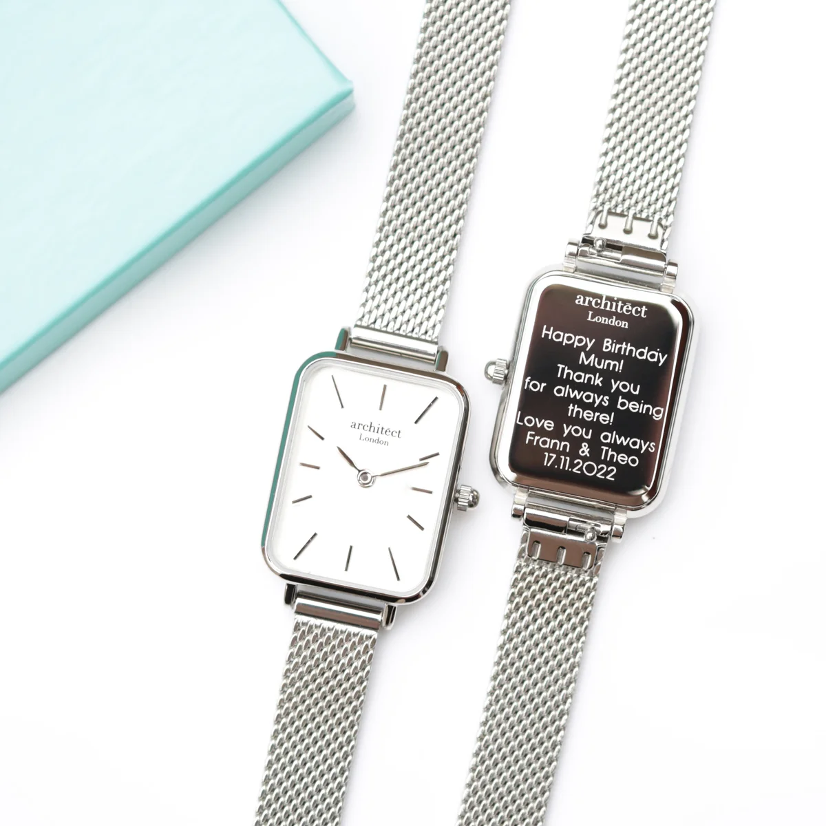 Engraved silver watch with modern font on polished stainless steel case and handcrafted silver mesh strap on white background