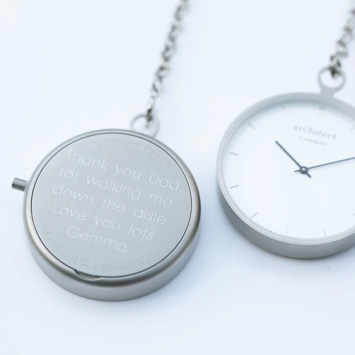 Modern silver engraved pocket watch with brushed stainless steel case and sapphire glass face showing Swiss movement dial