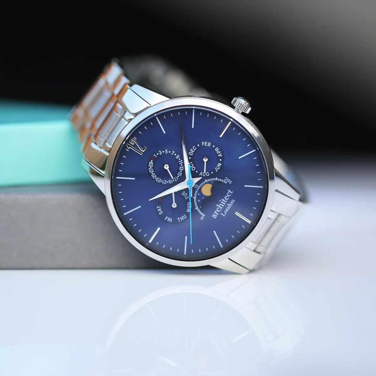 Blue dial engraved moonphase watch with silver stainless steel strap and three chronograph subdials on wrist