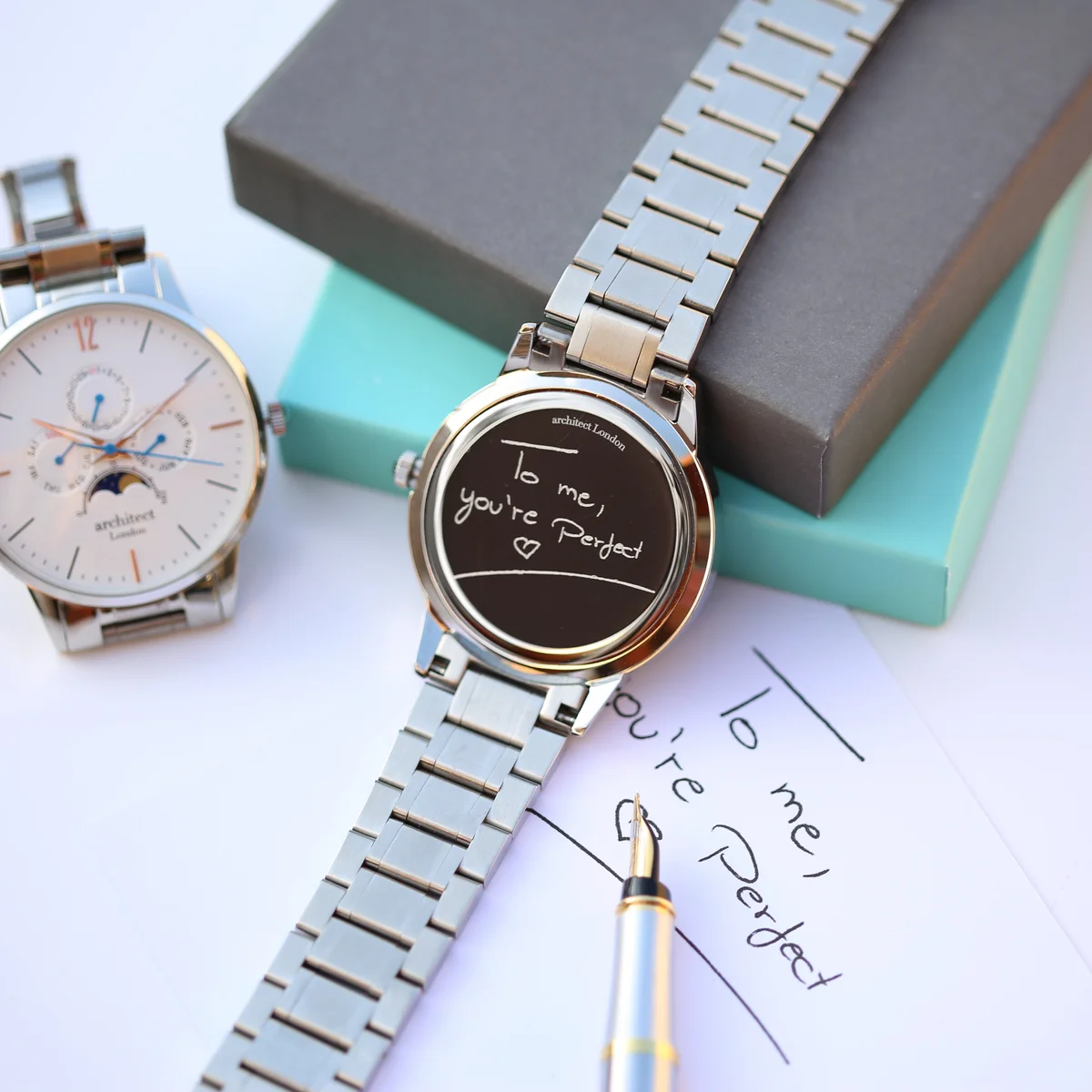 White dial engraved moonphase watch with silver stainless steel strap and three chronograph subdials on wrist
