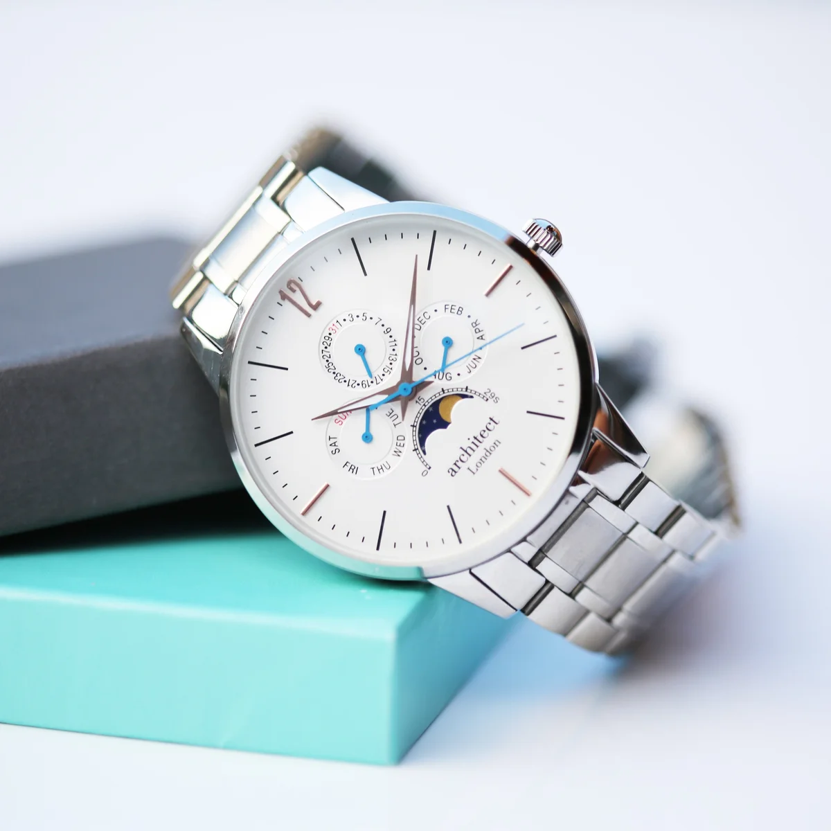 White dial stainless steel watch with moonphase and chronograph subdials, engraved back, silver strap, luxury box visible