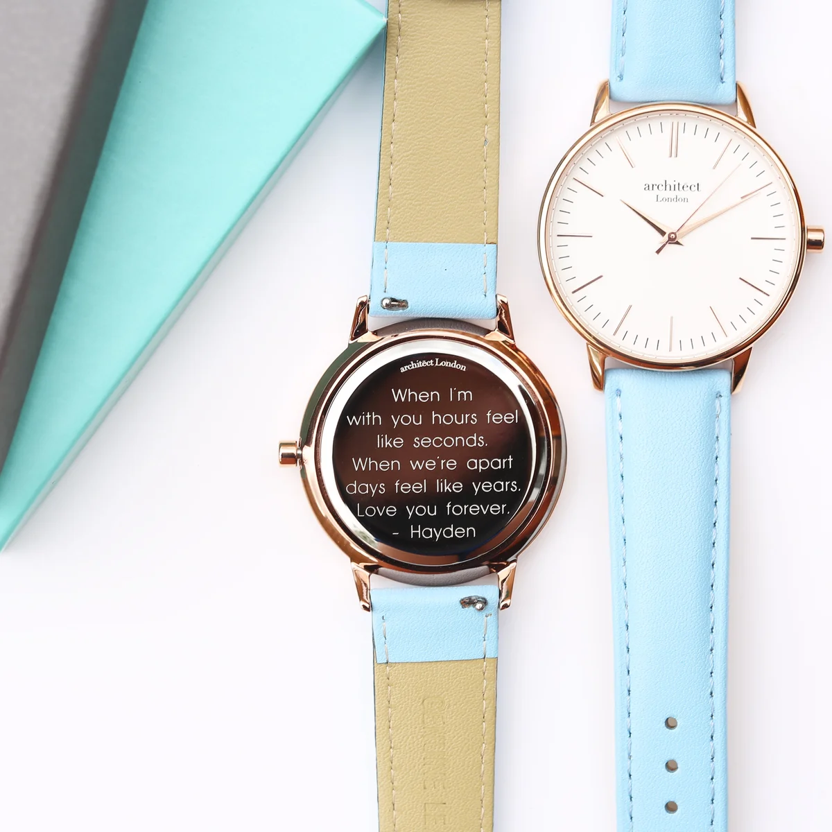 Ladies modern engraved watch with light blue leather strap, polished stainless steel case, and minimalist white dial
