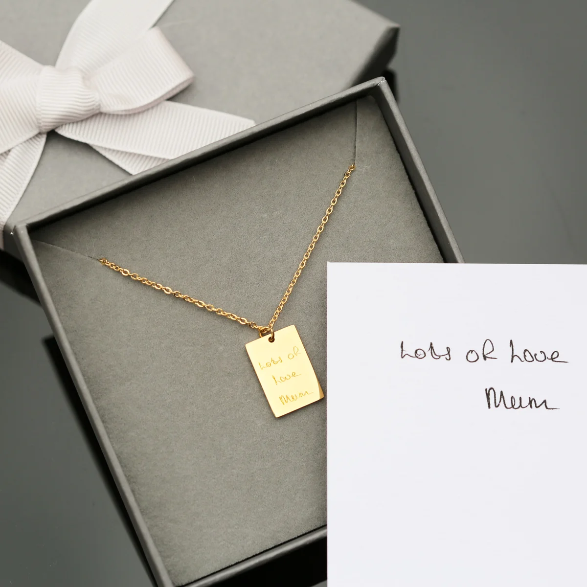 Sentimental personalised necklace in rose gold with delicate handwriting engraving on a 48cm chain and gift box background