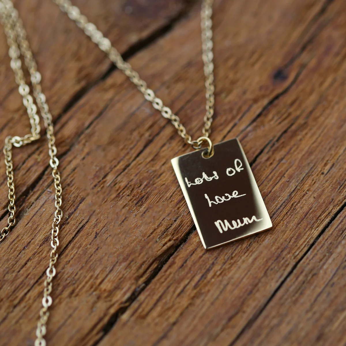 Close-up of personalised handwriting necklace in rose gold with delicate engraving on a 48cm chain and gift box background