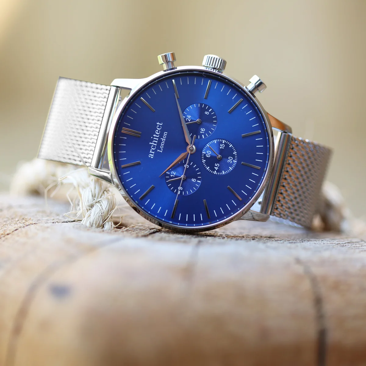 Men’s silver strap watch with deep-space blue dial, three chronograph subdials, and Milanese mesh band on white background