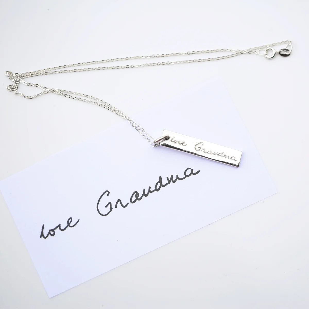 Engraved silver necklace featuring a fine 925 sterling silver bar with handwritten inscription, hanging on a silver chain.
