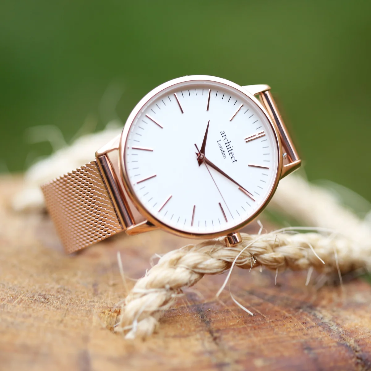 Ladies rose gold watch with minimalist white dial, stainless steel case, and rose gold mesh strap on white background