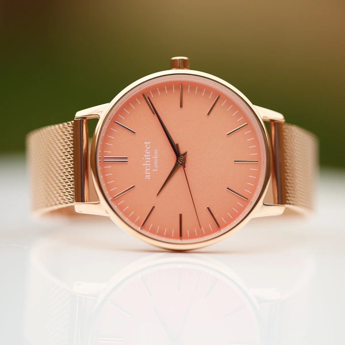 Ladies Coral watch with apricot dial and rose gold mesh strap on white background, minimalist design
